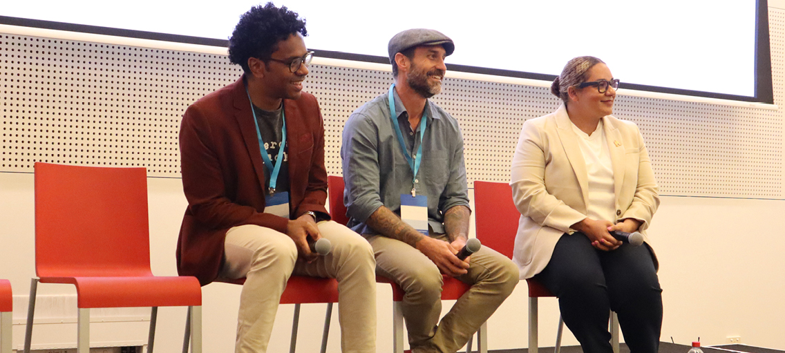 Photo of three people on a penal at a conference