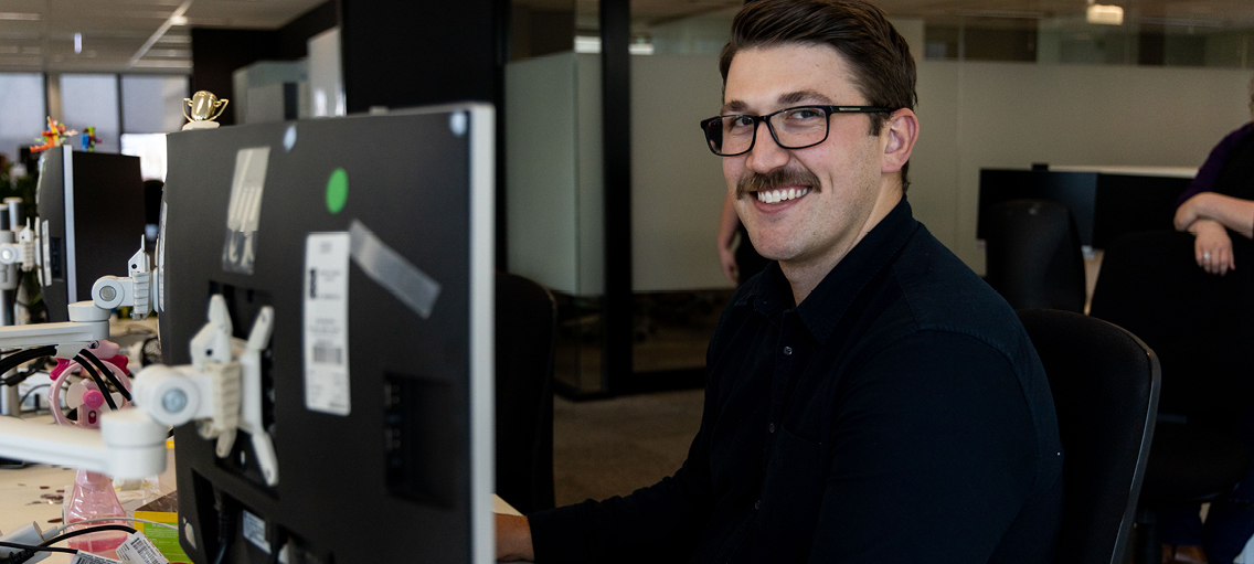 Photo of a staff member sitting at their desk smiling 