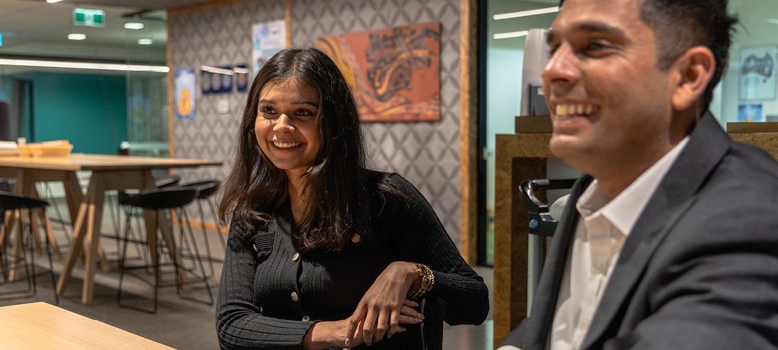 Photo of two staff members sitting at their desk smiling 